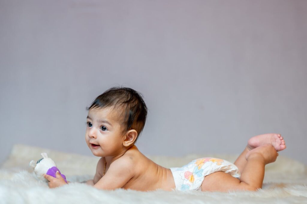 Cute baby in diaper holding toy while lying on a fluffy blanket. Perfect for baby and family themes.
